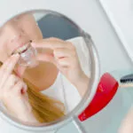 Woman placing a dental aligner in front of a mirror for orthodontic treatment and teeth straightening