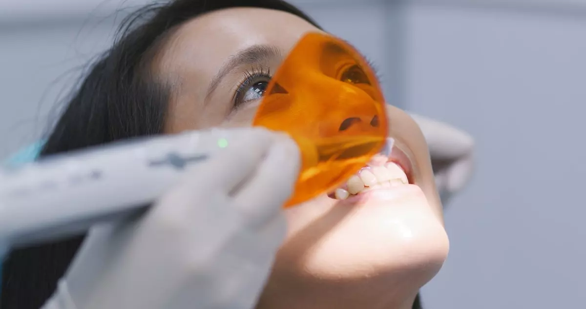 Dentist performing teeth whitening with curing light device