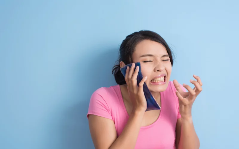 Woman holding ice pack to face for toothache relief