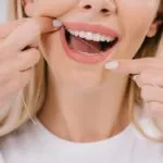 Woman practicing dental hygiene by flossing teeth.